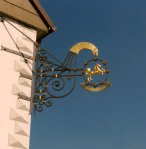 Schmiedeeiserner Ausleger mit Blechfigur, Vergoldungen & aufgemalten Fassadenornamenten